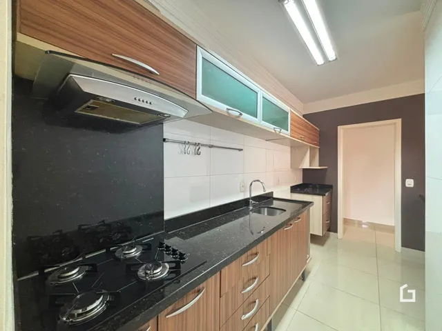 Vista da cozinha moderna com armários de madeira e bancadas escuras.