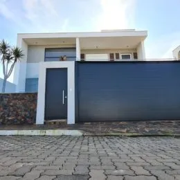 Fachada frontal de uma residência com garagem escura em Lajeado.