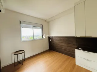 Ambiente interno de uma sala com piso de madeira e janela com vista para a paisagem.