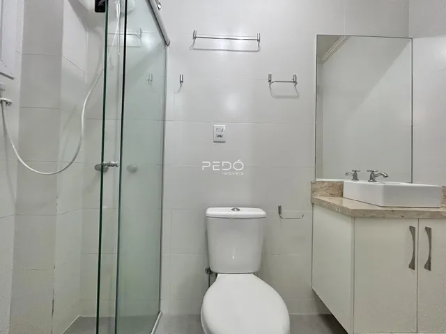 Banheiro com box de vidro e revestimento branco.