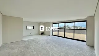 Uma foto de um espaço interno amplo e vazio com paredes brancas e piso de concreto.