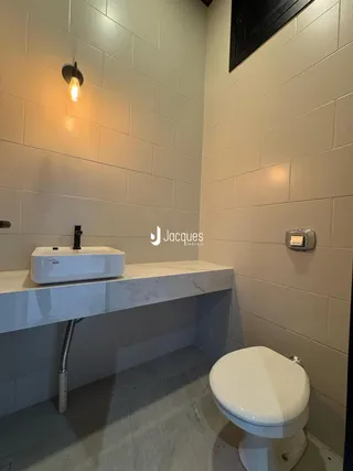 Banheiro com revestimento de azulejo branco e bancada de mármore.