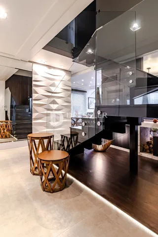 Uma sala de estar moderna com piso de madeira escura e divisórias de vidro.