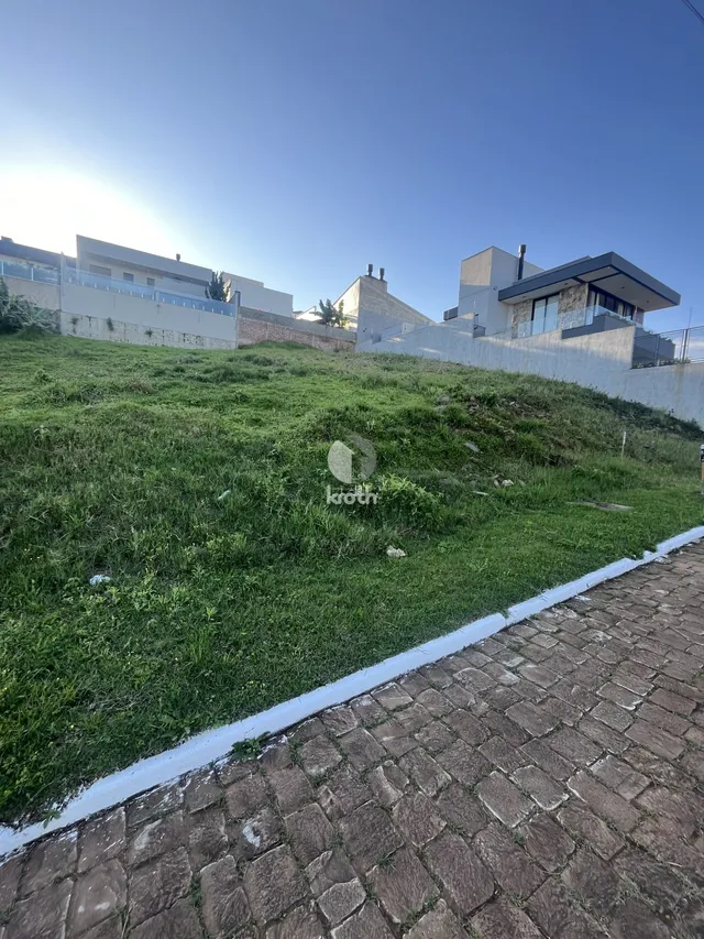 Vista externa de uma propriedade com gramado e muro de fundo.