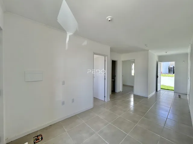 Hall de entrada com piso de cerâmica clara e paredes brancas.