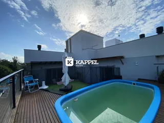 Foto da área externa com piscina e deck de madeira em uma residência.