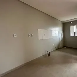 Foto interna de um corredor com paredes brancas e piso claro.