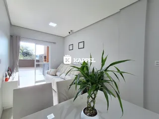 Uma sala de estar clara com sofá e vista para o exterior.