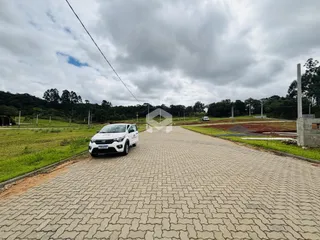 Vista da entrada de uma propriedade com estrada pavimentada e área gramada