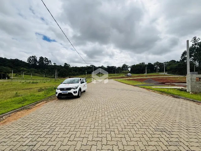 Vista da entrada de uma propriedade com estrada pavimentada e área gramada