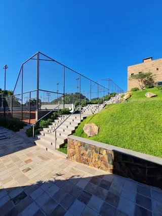 Vista externa de uma propriedade com jardim e escadaria de pedra.