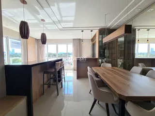 Sala de jantar com mesa de madeira e grandes janelas.
