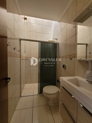 Foto de um banheiro com revestimento cerâmico e box de vidro.