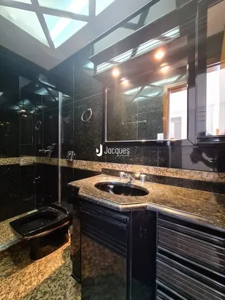 Foto de um banheiro com revestimento escuro e bancada de granito.