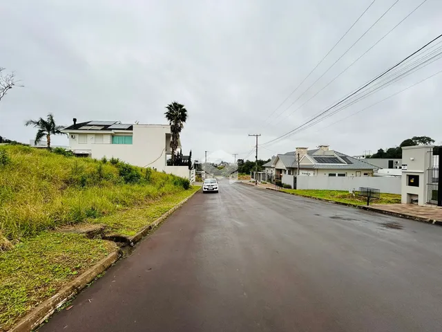 Vista de uma rua em Lajeado, Brasil, mostrando casas e vegetação ao longo da via.