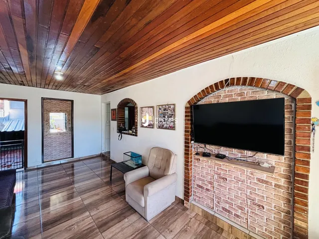 Sala de estar com teto de madeira e arco de tijolos na parede.