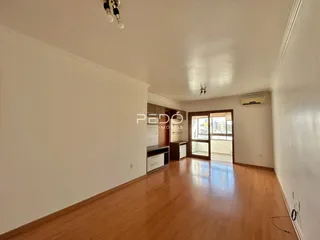 Sala de estar com piso de madeira e paredes brancas.