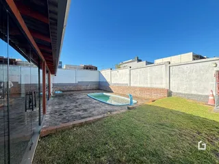 Vista externa de uma área de lazer com piscina e gramado.
