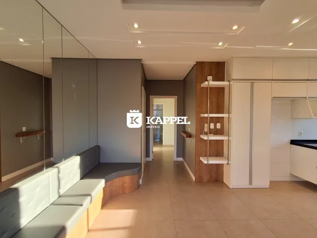 Sala de estar moderna com sofá e armários brancos em um ambiente claro.