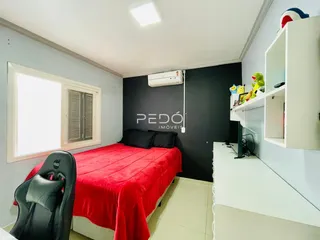 Quarto com cama vermelha e janela em ambiente claro.