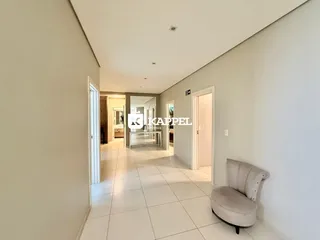 Hall de entrada com piso claro e paredes brancas, mostrando a profundidade do corredor.