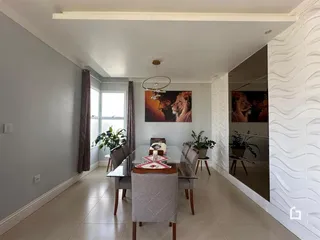 Vista interna de uma sala de jantar com grandes janelas e decoração moderna.