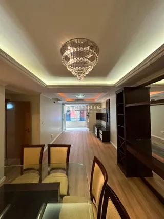 Hall de entrada com piso de madeira e lustre decorativo.