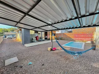 Vista externa de uma área com piscina sob uma estrutura de cobertura.