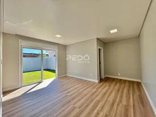 Sala de estar com piso de madeira e porta de vidro abrindo para o jardim.
