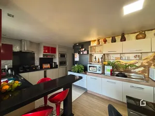 Vista da cozinha moderna com armários brancos e bancadas escuras.