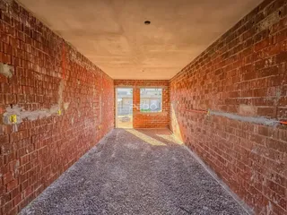 Vista de um corredor interno com paredes de tijolo aparente.
