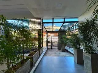 Vista de um espaço interno com acesso a uma área externa ajardinada.