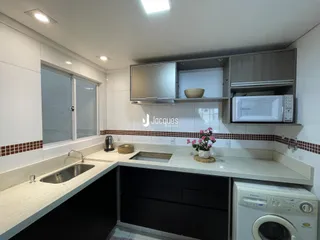 Foto da cozinha com armários brancos e bancadas claras.