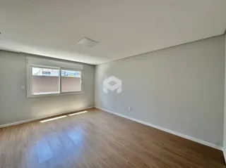 Vista interna de uma sala de estar com piso de madeira clara e janela.