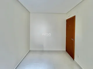 Corredor interno de um imóvel com paredes brancas e piso de cerâmica.