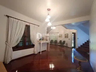 Sala de estar com piso de madeira e grandes janelas.