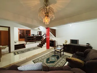 Interior da sala de estar com escadaria e móveis de madeira.