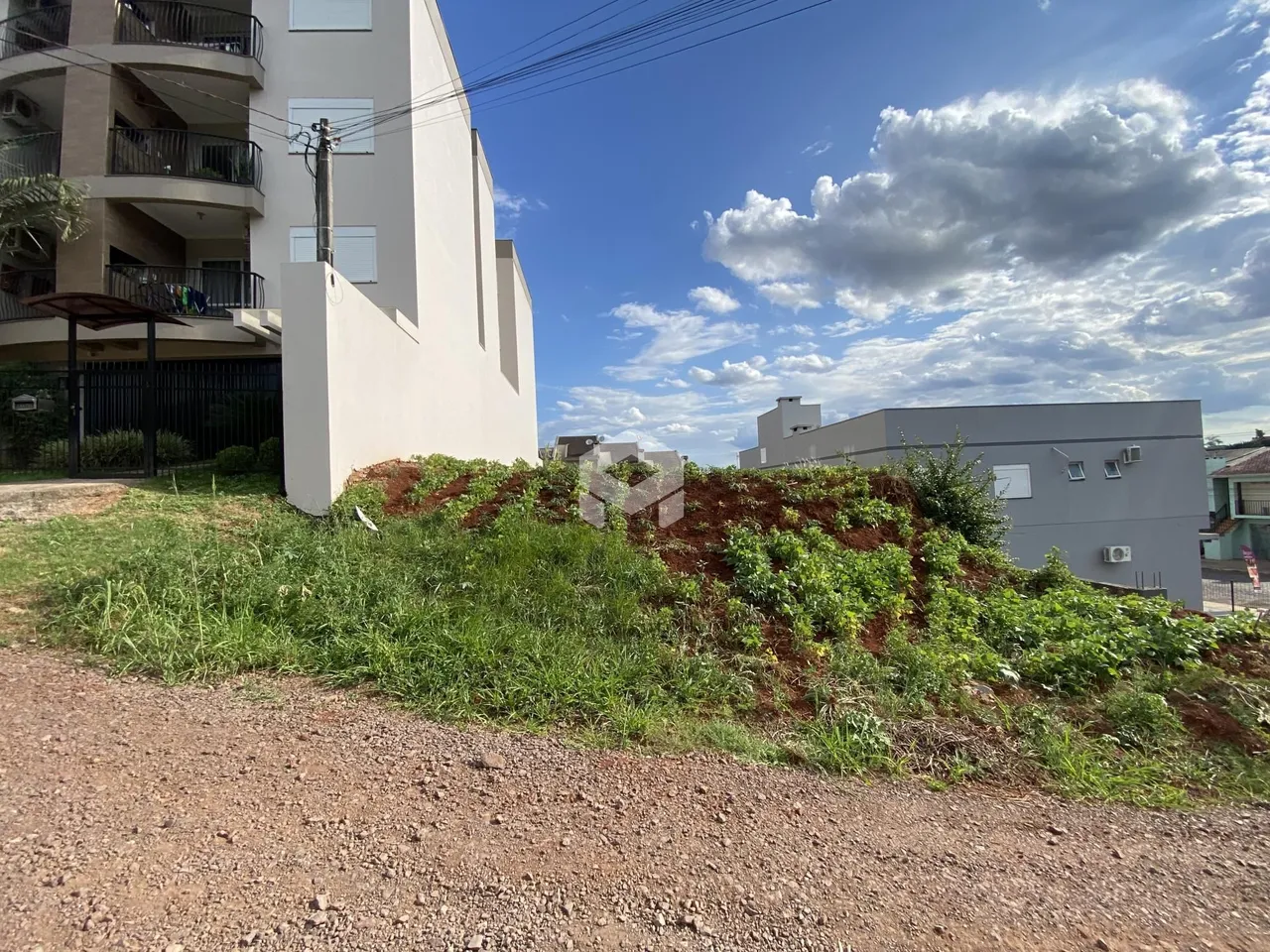 Fachada de um prédio residencial com vegetação no primeiro plano.