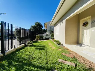 Fachada de uma residência com jardim gramado e cerca de ferro.