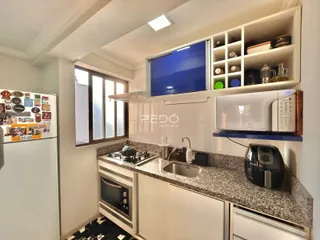 Vista da cozinha com armários brancos e bancada de granito.