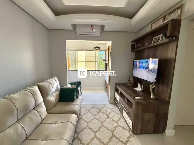 Sala de estar com sofá e rack de TV em ambiente claro.