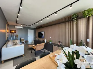 Sala de estar moderna com parede de ripas de madeira e sofá claro.