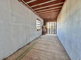 Corredor interno com paredes brancas e teto de tijolo aparente.
