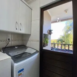Foto de um ambiente de cozinha com armários brancos e uma máquina de lavar.