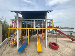 Estrutura de playground externa com escorregadores e balanços em uma área externa.