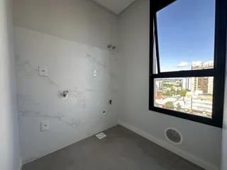 Corredor com paredes de mármore branco e grande janela com vista para a cidade.