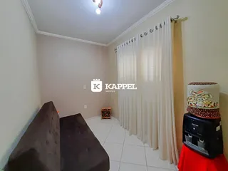 Sala de estar com sofá escuro e cortinas brancas.
