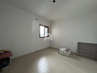 Interior de um cômodo com paredes brancas e piso de cerâmica.