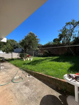 Vista externa mostrando um gramado verde e vegetação sob um céu azul claro.