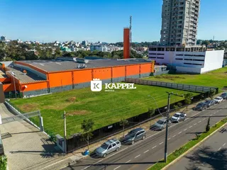 Vista externa de um terreno com um prédio de cor laranja e área gramada.